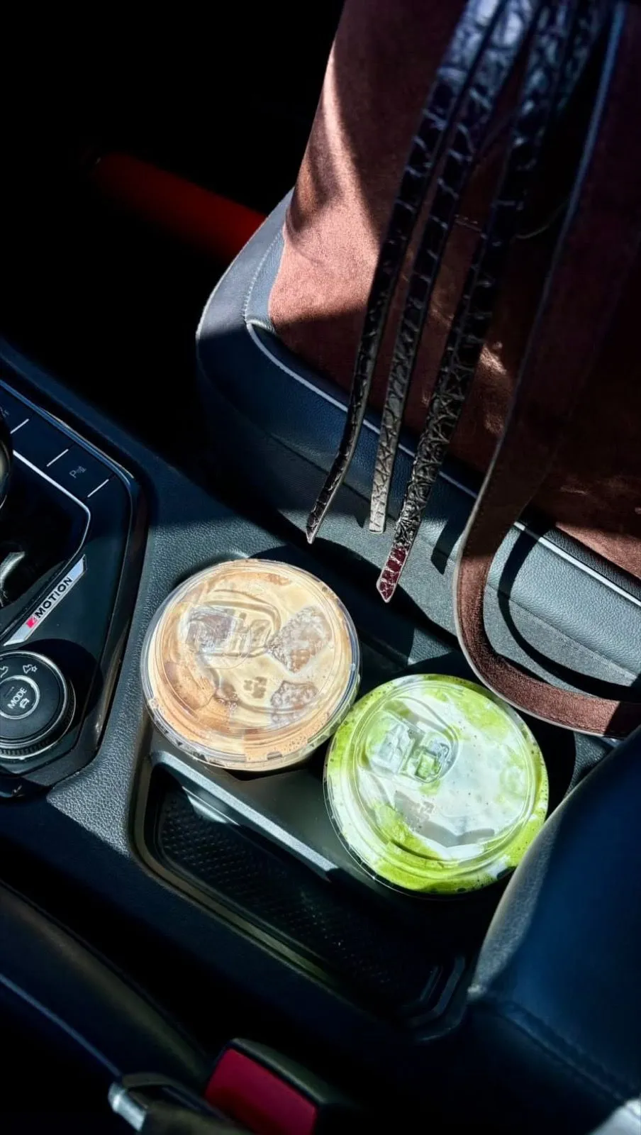 Un café y un matcha de andy & dany en el portavasos de un auto